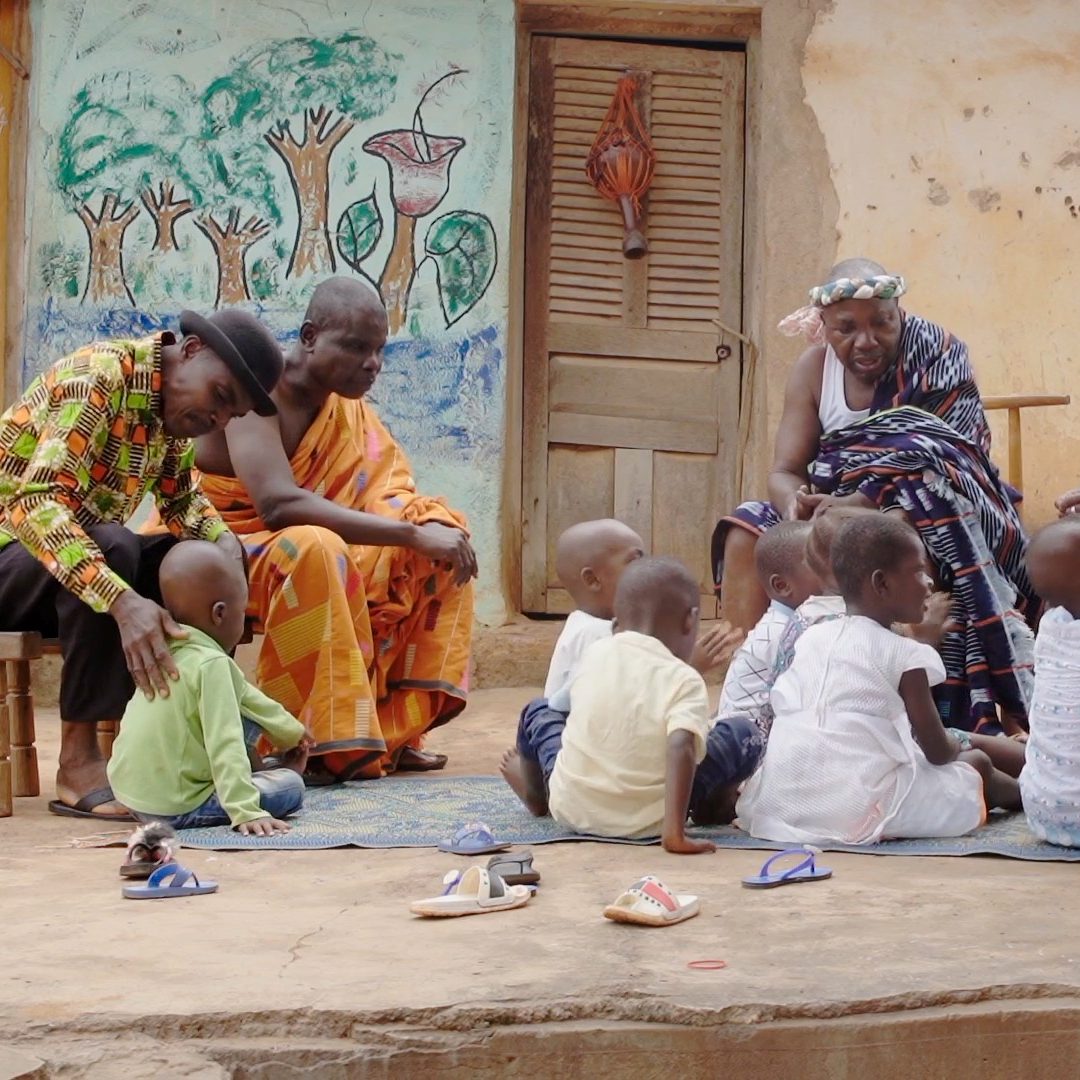 Village elders play with their children in rural Cote dIvoire