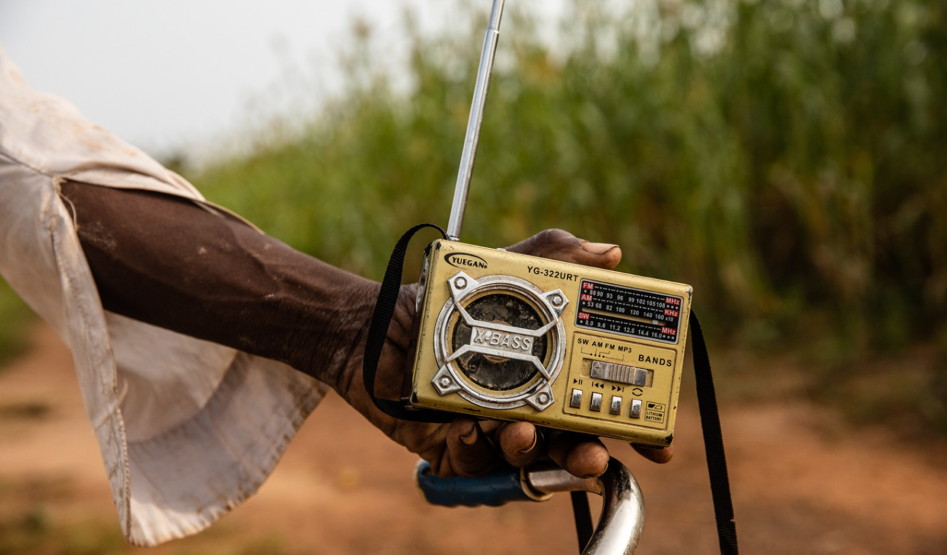 Man holding radio field Burkina Faso representing DMIs method of communication for this campaign