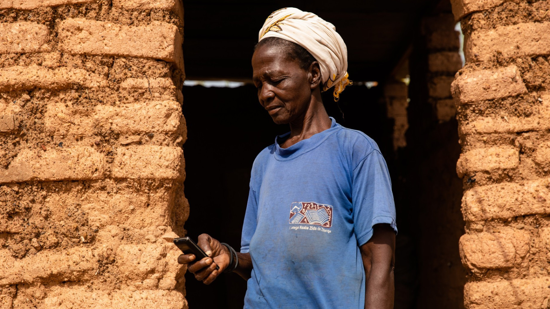 A woman holding a mobile phone demonstrating DMI's use of phones to distribute video campaigns