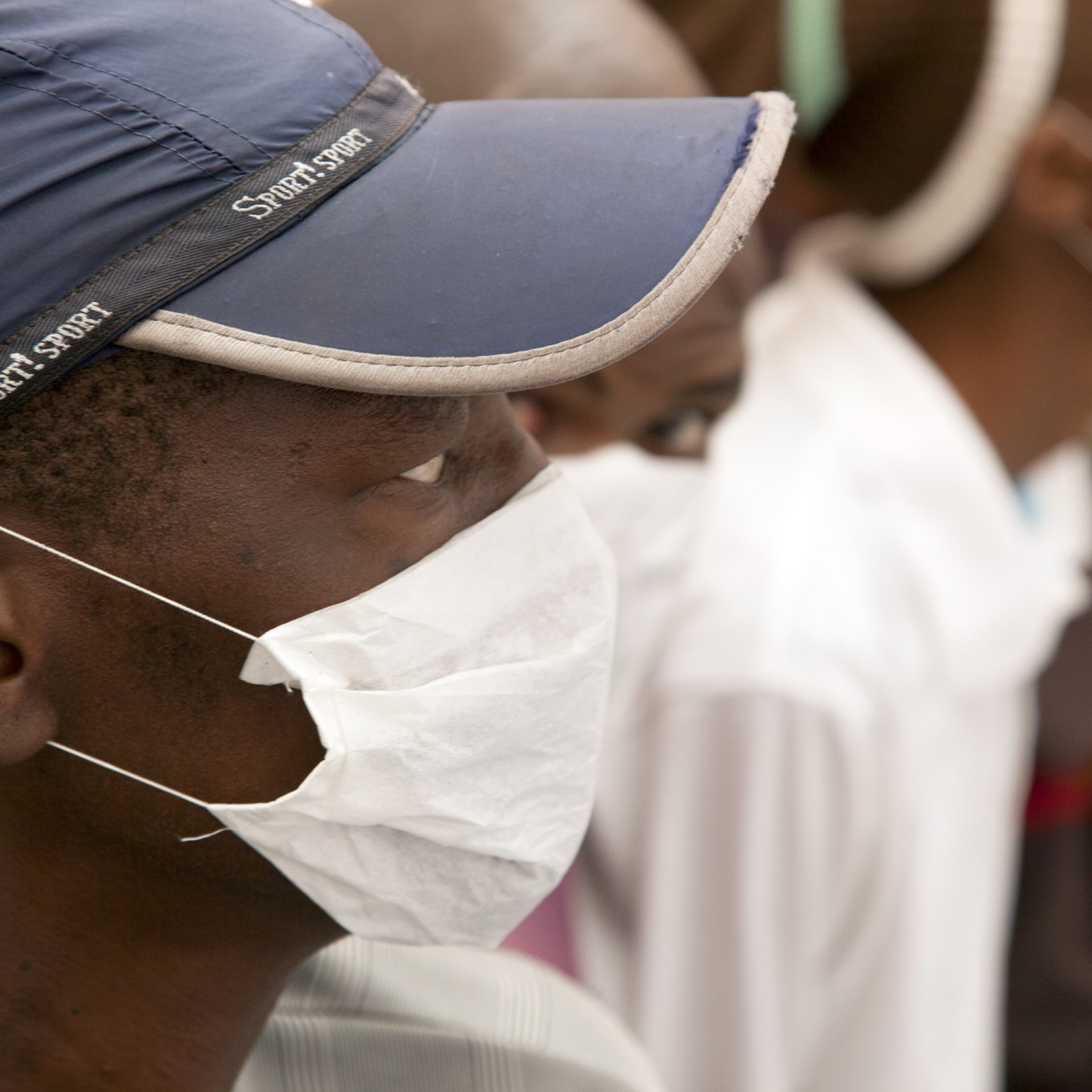A TB patient wearing a mask demonstrating DMI's work with TB